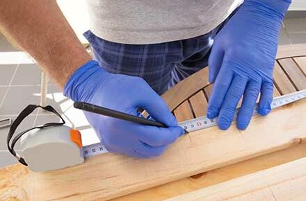 Carpenter marking wooden desk with measuring tape and pen for drilling or saw cut. Closeup shot of male hands. Carpentry work or assembling furniture concept